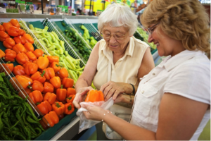 senior lady and caregiver grocery shopping for produce