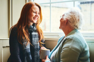 Young caregiver talks to senior woman about the advantages of home health care.