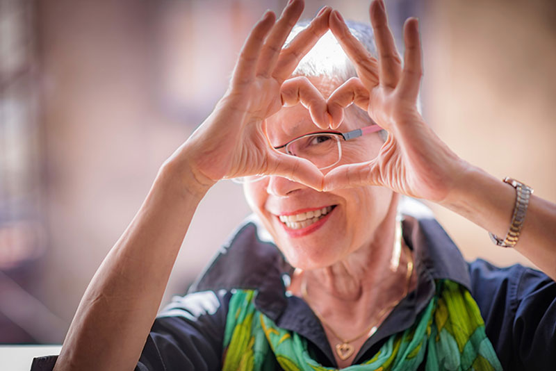 happy lady looking through heart made with hands