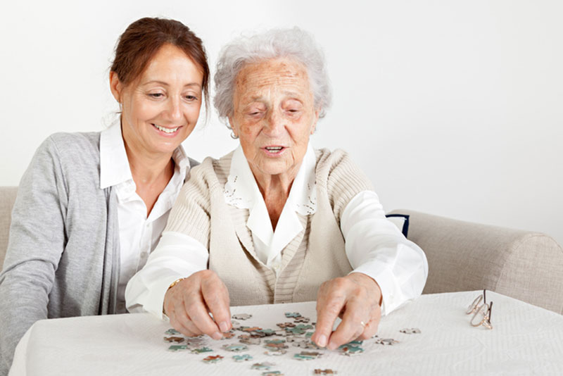 A woman puts together a puzzle with her older mother. This is just one of the activities for a person with dementia to help build confidence.