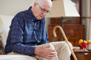 An older man massages his sore knee while preparing for a joint replacement procedure.
