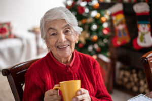 A senior woman enjoys a cup of tea in her home which is decorated for the holidays. Her family knew what signs to watch for and with in-home care services, she is able to continue to live independently.