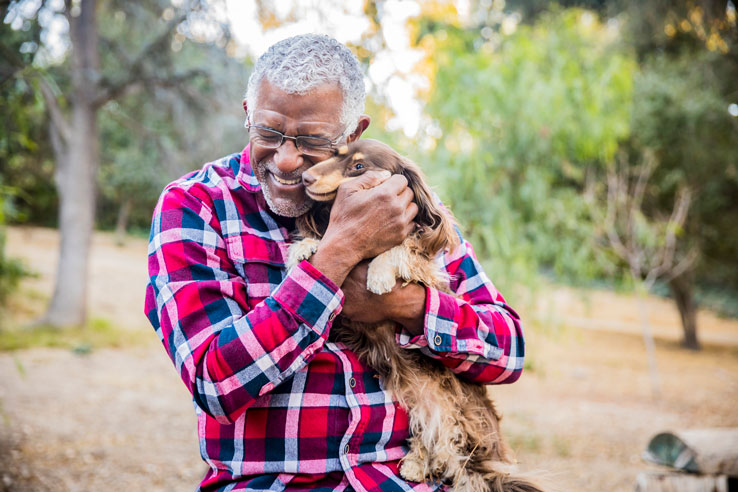 older man holding a playful puppy to help relieve senior stress